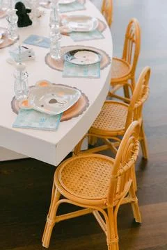 Charming childrens party table setting with animal-themed plates and cozy wicker Foto stock