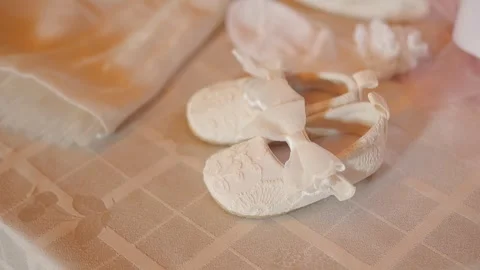 Charming Closeup of Delicate Tiny White Baby Shoes on Lace Fabric Stock Footage 329657756
