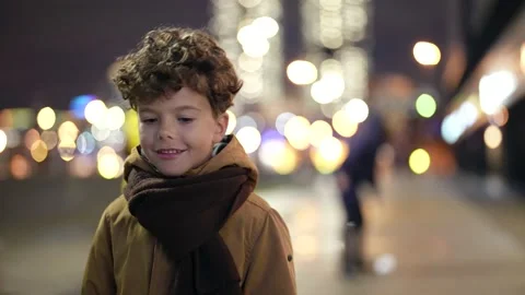 Charming curly little boy is strolling in city in evening, portrait of funny Видео 166095407
