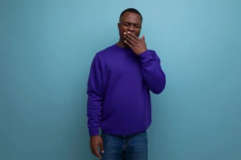 Charming cute young african guy in a blue sweatshirt on the background with copy Stock Photos