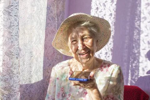 Charming elderly woman in rectangular black rimmed eyewear using voice recogn Foto stock