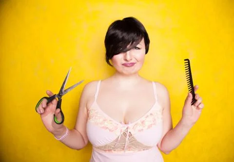 Charming emotional plus size woman cuts her hair with scissors because she wants Stock Photos