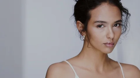 Charming female model putting cosmetic on her cheek and wind blows her black Stock Footage 123732374