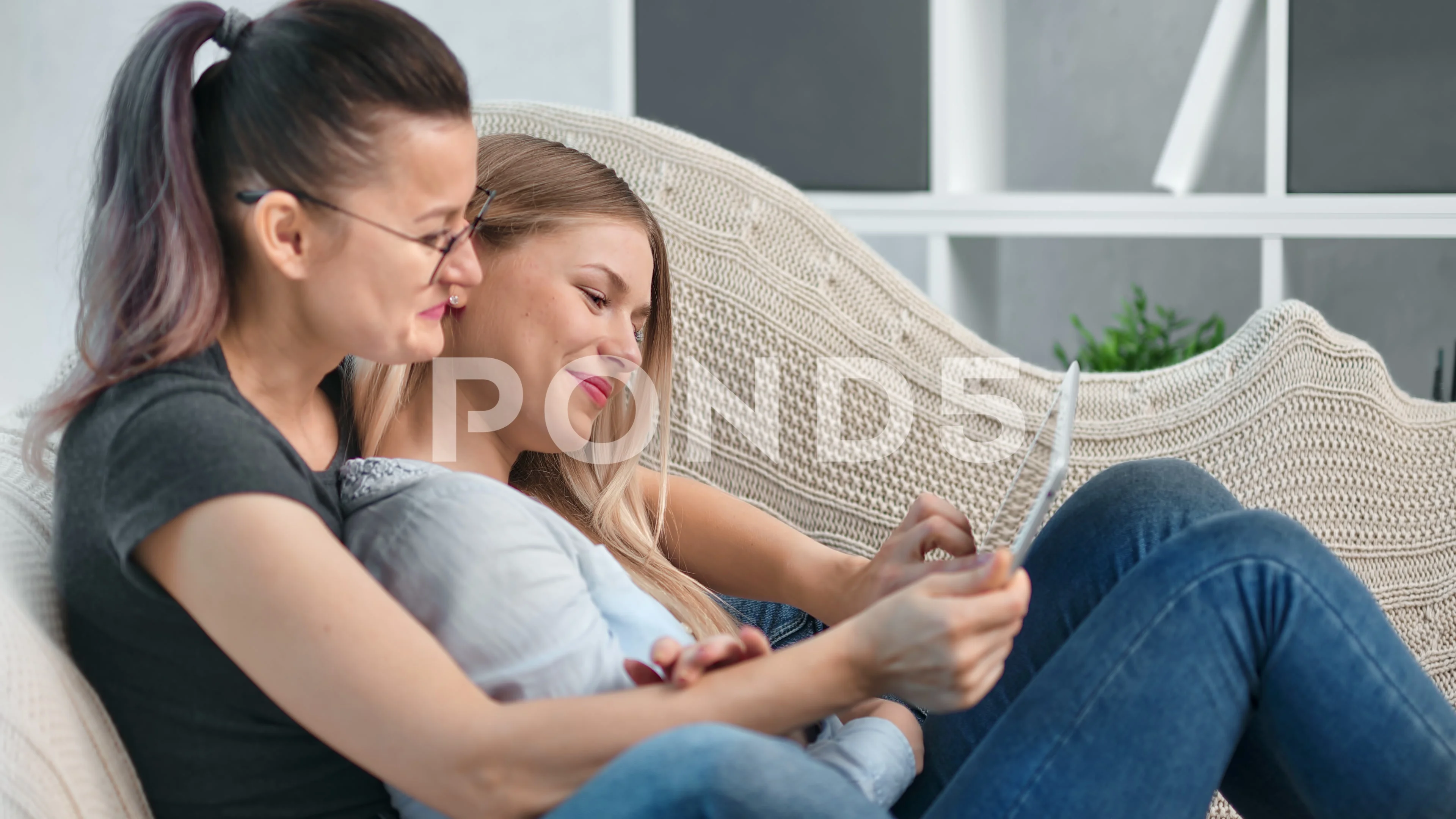 Charming female same sex couple relaxing together having tenderness using  tablet