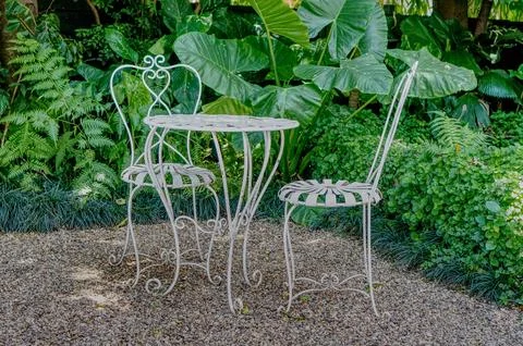 A charming garden scene featuring a table and chairs set, surrounded by lus.. Foto stock