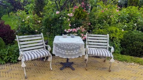 Charming Garden Setting with Rustic White Benches and a Lace-Covered Table Stock Photos