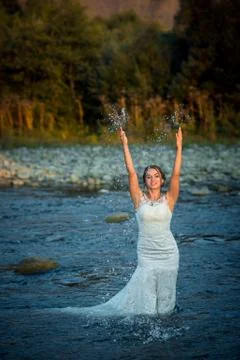 Charming ginger head bride in the wedding dress is splashing water while Stock Photos