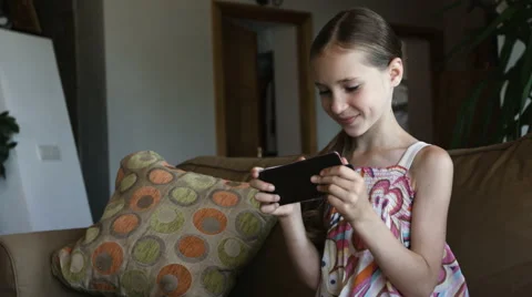 Charming girl playing tablet pc sitting on sofa in living room at home, close-up Stock Footage 65880880