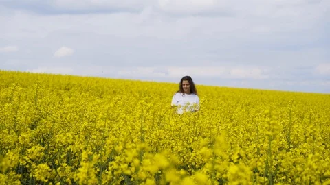 Charming girl walking through rape field Stock Footage 119658786