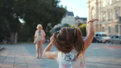 Charming granddaughter running down the street to beloved grandmother with Stock Footage