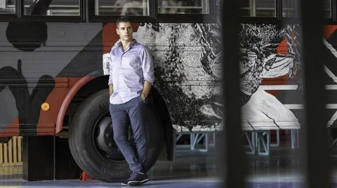 A charming guy posing in front of a stylish urban bus full of graffiti. Lisbo Foto stock