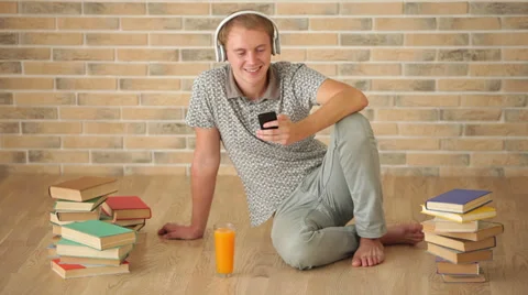 Charming guy sitting on floor using mobile phone looking at camera and smiling Stock Footage 34278052