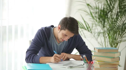 Charming guy sitting at table with books and studying Video stock 28791593