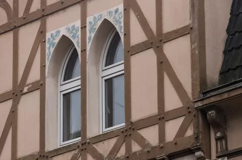 Charming half-timbered house showcasing two arched windows with delicate blue Stock Photos