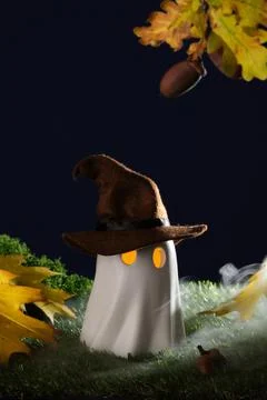 A charming Halloween ghost in a witch's hat with glowing eyes surrounded by a Stock Photos