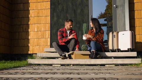 Charming happy young couple in love sitting on steps near modern house and Stock Footage 121662053