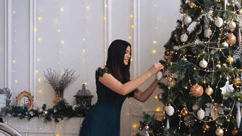 Charming lady is decorating the Christmas tree in the luxurious interior Stock Footage