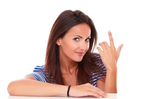 Charming lady with finger pointing up and looking at camera in white backgrou Stock Photos