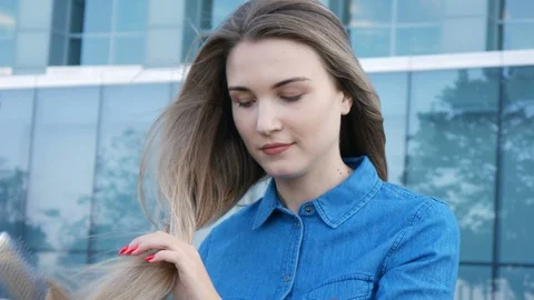 Charming lady trying to comb brush her hair in a heavy wind 스톡 동영상 101241649