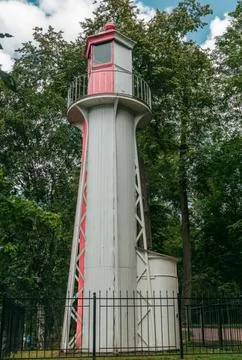 A charming lighthouse tower stands prominently amid greenery in a peaceful pa Stock Photos