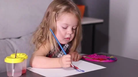 Charming little blonde girl in red checkered dress, painting with colorful Stock Footage
