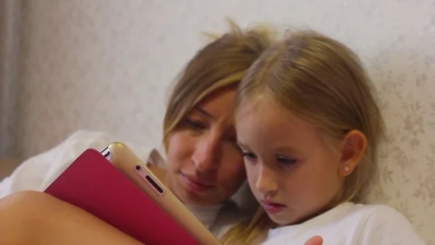 Charming little girl and her beautiful young mom are using a digital tablet and Stock Footage
