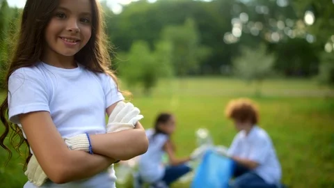 Charming little girl posing for camera with mates cleaning behind Stock Footage