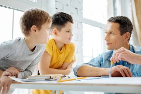 Charming man communicating with children while working Stock Photos