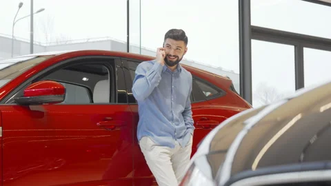 Charming man talking on his smart phone while choosing new car at the dealership Stock-Footage 147547980