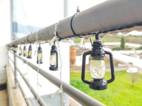 Charming miniature lantern string lights adorn a balcony railing on a rainy d Stock Photos