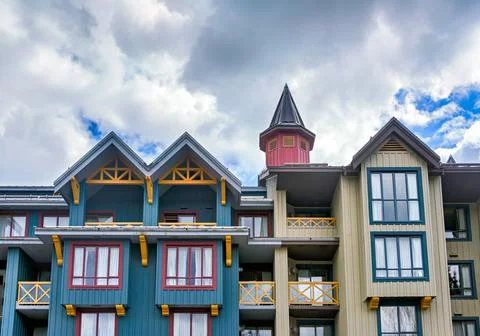 Charming Multi-Gabled Alpine Chalet Condominium Under Cloudy Sky Stock Photos