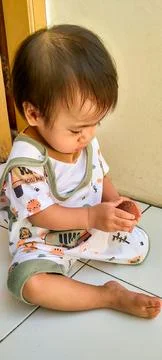 Charming One Year Old Child Playing with Lychee Fruit Outside Foto stock