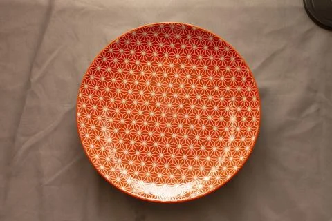 Charming orange patterned ceramic dish illuminated softly for product showcasing Stock Photos