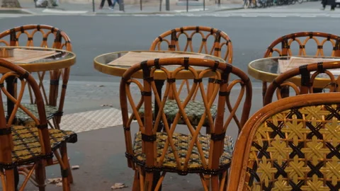 Charming Outdoor Cafe Scene with Wicker Furniture and Passersby Stock Footage 318556259