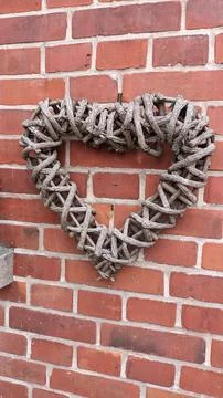 Charming Rustic HeartShaped Wicker Wall Decor on a Brick Wall adding bohemian Stock Photos