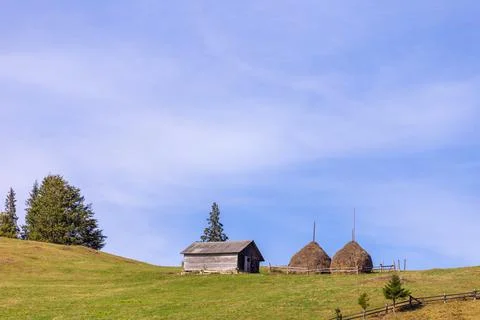 Charming Rustic Scene Featuring a Quaint Wooden Cabin and Traditional Haystacks Stock Photos