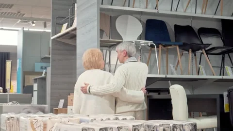 Charming senior couple joyfully selecting furniture together in a cozy store Stock Footage 311673572