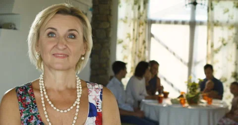 Charming senior woman posing on the camera and family sitting at dinning table Stock Footage 66289698