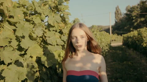 Charming slim girl in a strapless dress walks along the vineyards Stock Footage 59383430