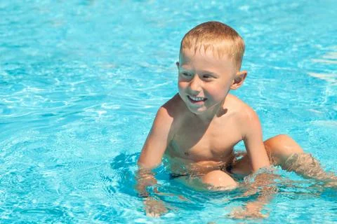 Charming smiling boy sitting into the pool Stock Photos