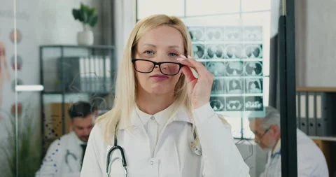 Charming smiling high-skilled blond female doctor taking off glasses and looking Stock Footage 160476331