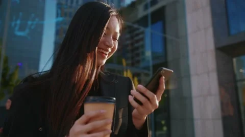 Charming smiling woman walking while using phone hold drink coffee in urban city Stock Footage 156737231