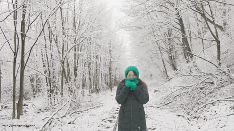 In a charming snow-covered forest, a young woman strolls outdoors, enjoying the Stock Footage 247314173