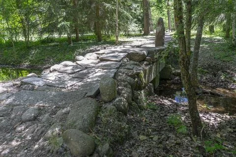 A charming stone bridge spans a small stream in the tranquil Finnish Forest.. Stock Photos