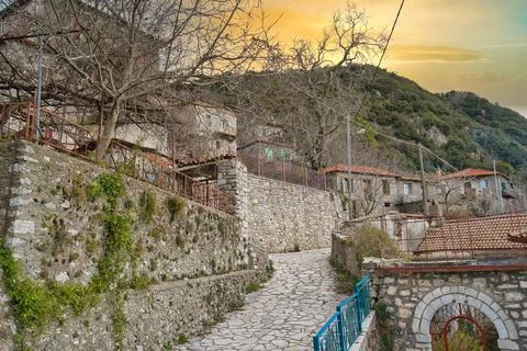 Charming stone pathway leading through historic village at sunset in Dimits.. Stock Photos