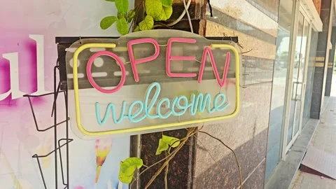 Charming storefront neon sign with "OPEN" in warm orange and "welcome" in teal Video stock 333414934