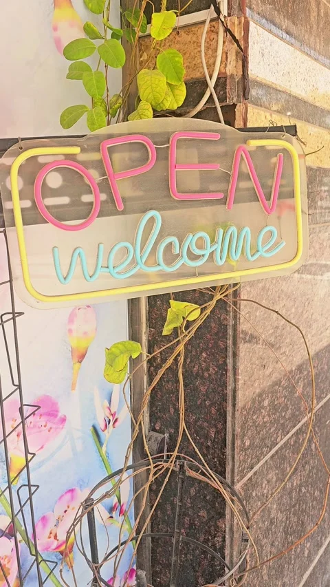 Charming storefront neon sign with "OPEN" in warm orange and "welcome" in teal Video stock 333415698