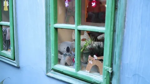 A charming view through a green-framed window showcasing handmade plush toys, wo Stock Footage 294785059