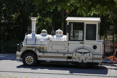 Charming white miniature train engine on a sunny day with lush green trees Fotos Stock