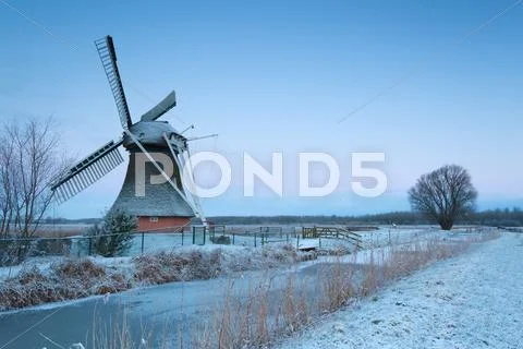 Charming windmill in winter at sunrise Stock Photos